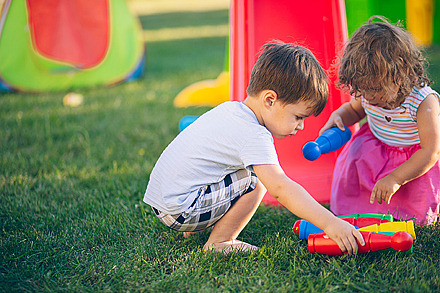 Impfungen für Kinder schützen vor Infektionskrankheiten. Zwei Kinder spielen im Freien