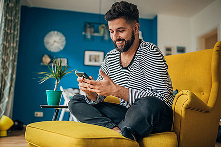 Alle wichtigen Informationen auf einen Blick Ein lachender Mann schaut auf sein Smartphone