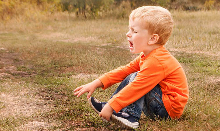 Ein kleiner Junge sitzt auf einem Weg und weint.