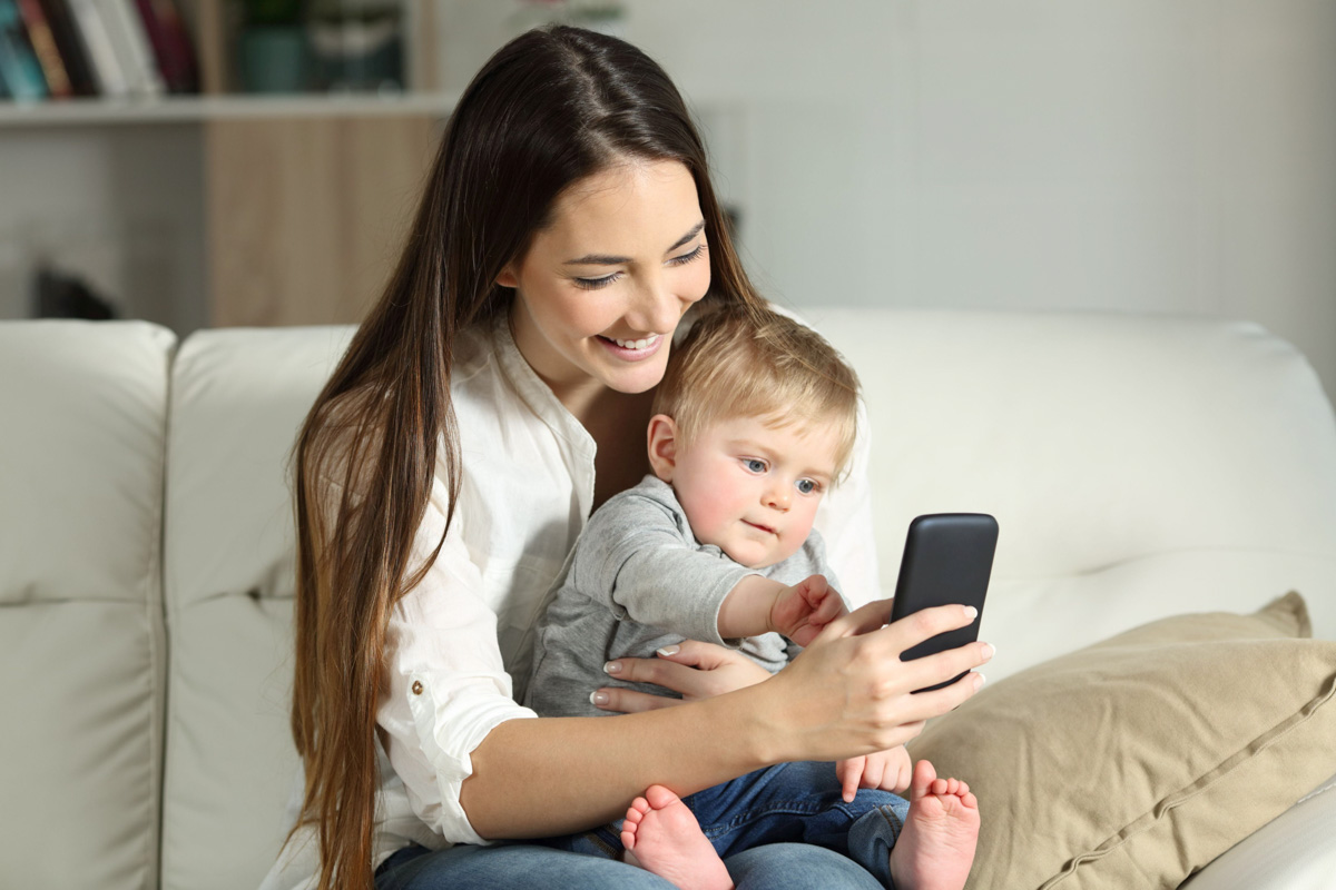 Kein Problem: Gemeinsam mit den Großeltern per Video sprechen oder digitale Familienfotos ansehen Mutter und Kleinkind schauen auf ein Smartphone